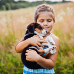 Little girl holds a puppy on her arms